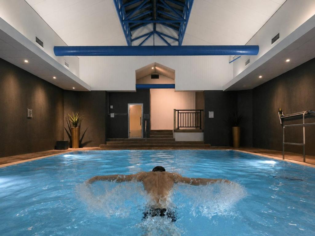 a man in a swimming pool in a building at Sandman Signature London Gatwick Hotel in Crawley