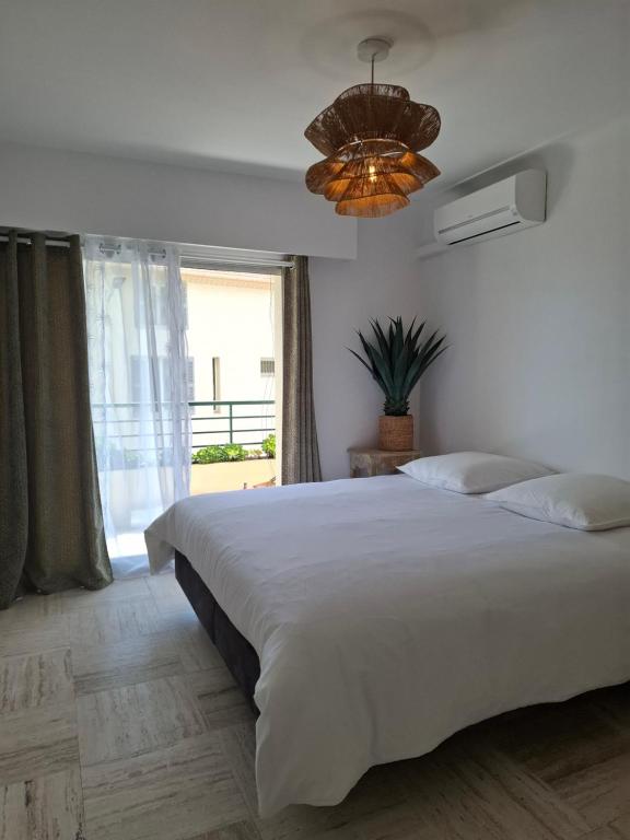 a bedroom with a large white bed and a chandelier at Cannes à Pied in Cannes