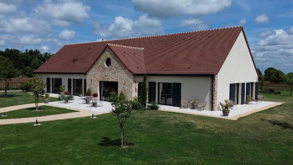 a house with a red roof and a green yard at Aux 3 Forêts in Bizeneuille