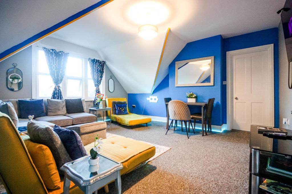 a living room with blue walls and a couch and a table at Vibrant - 8ight Havens in Folkestone