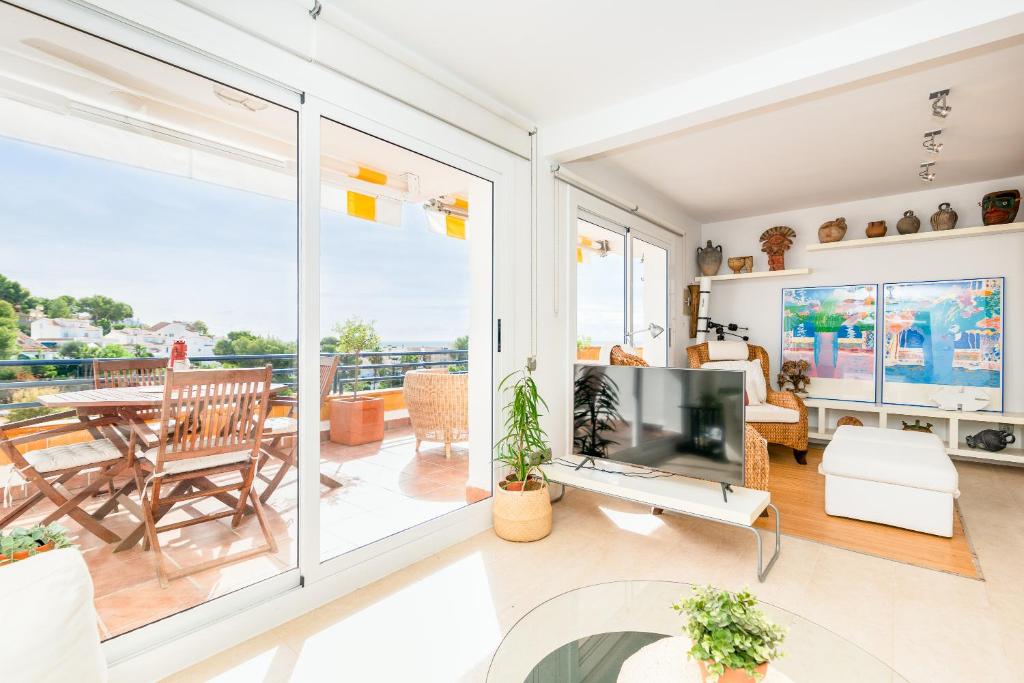 a living room with a television and a balcony at Marvista - Bright Apt w Seaview, Pool in Sant Pere de Ribes