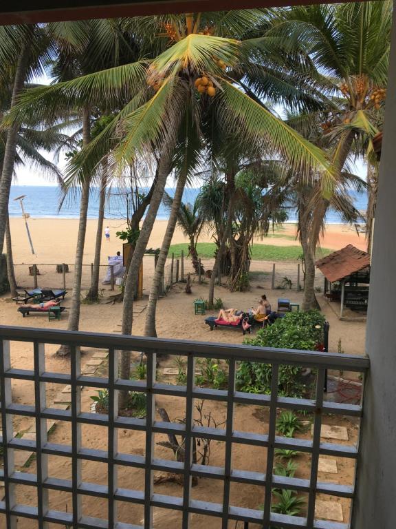 een balkon met uitzicht op een strand met palmbomen bij Dephani Beach Hotel in Negombo