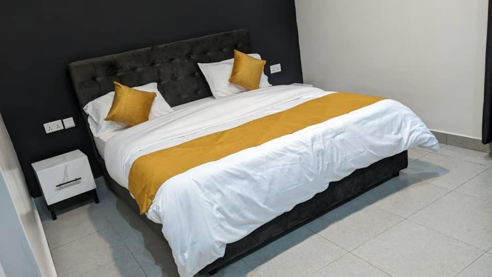 a large bed with yellow and white sheets and pillows at Mansarda Park View Hotel in Nyagatare