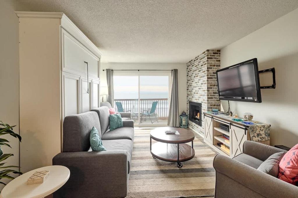 a living room with couches and a flat screen tv at Oceanfront Condo - Second Floor - Pet Friendly in Lincoln City