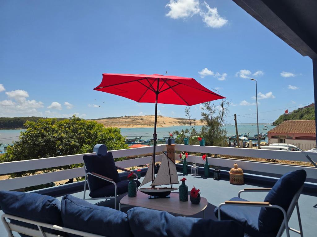 a table with a red umbrella on a balcony at lagoon apartment 4 in Moulay Bousselham