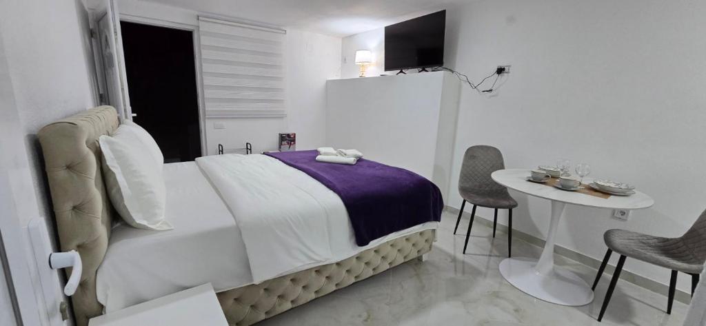 a bedroom with a bed and a table and chairs at Airport Apartment Masa in Mitrovići