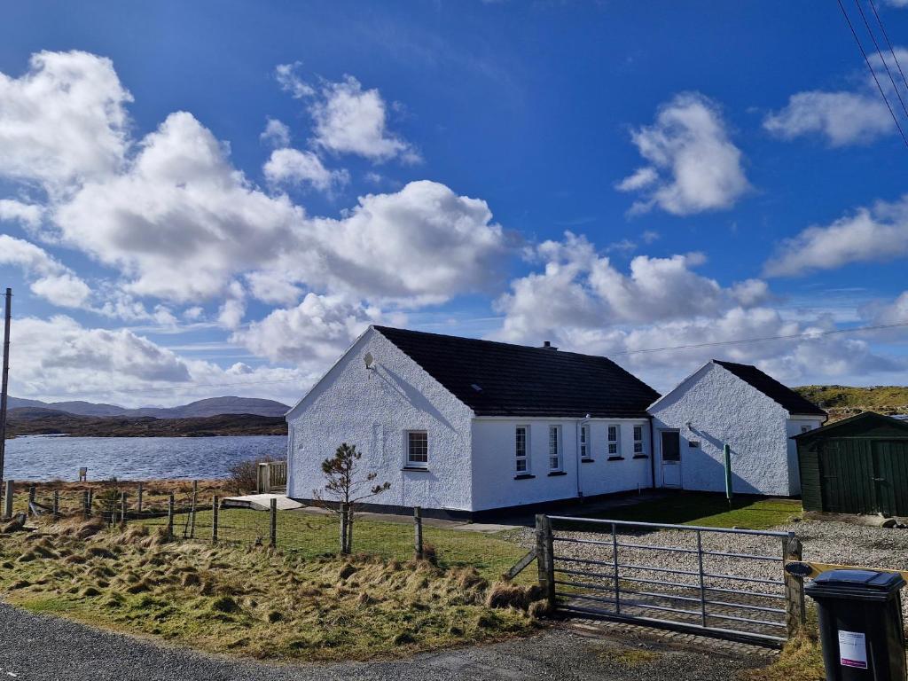 a white house next to a body of water at Lochan View Cottage in Breaclete