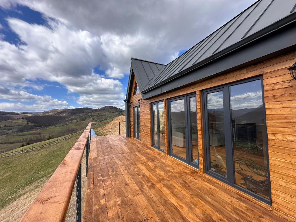 a wooden deck of a house with a view at Dor de Munte in Vărtăneşti