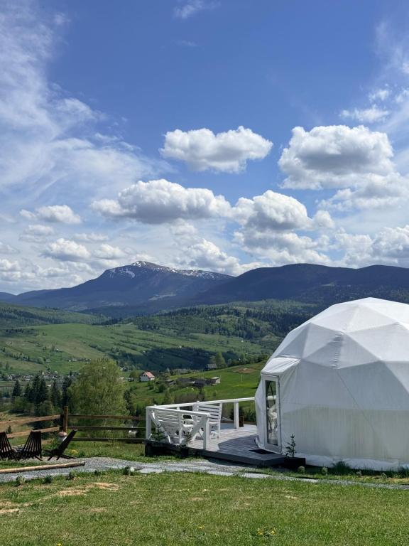 a large white tent with mountains in the background at Forest glamp in Yasinya