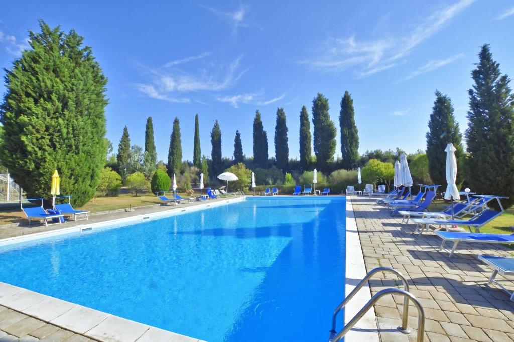 a large swimming pool with blue chairs and trees at Casa Guna - Happy Rentals in Asciano