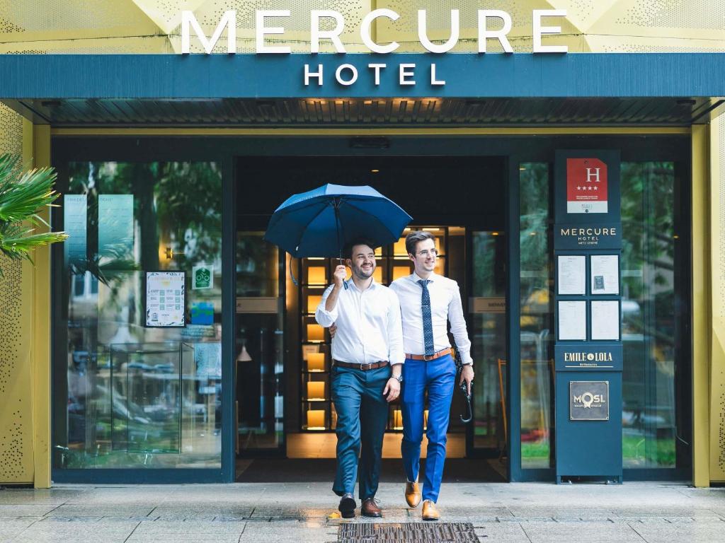 two men walking in front of a hotel with an umbrella at Mercure Metz Centre in Metz