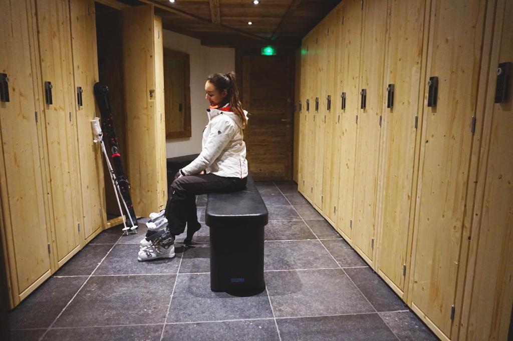 a woman sitting on a bench in a locker room at Le Chalet Blanc in Megève