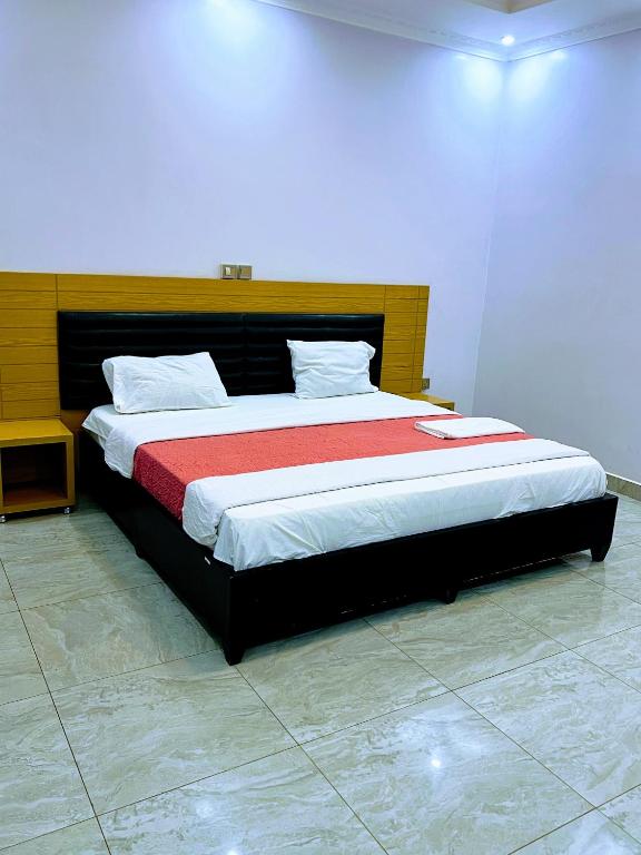 a bedroom with a large bed with a red blanket at Keys Apartments Kigali in Kigali