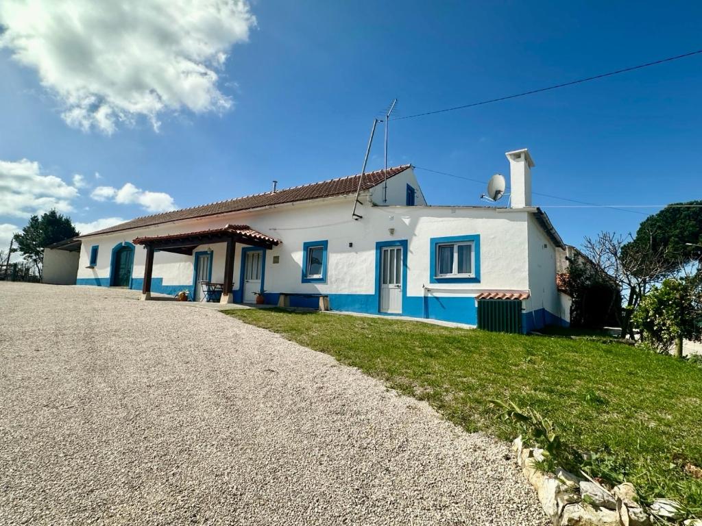 a white and blue house with a gravel driveway at Casal do Pequeno in Alcobaça