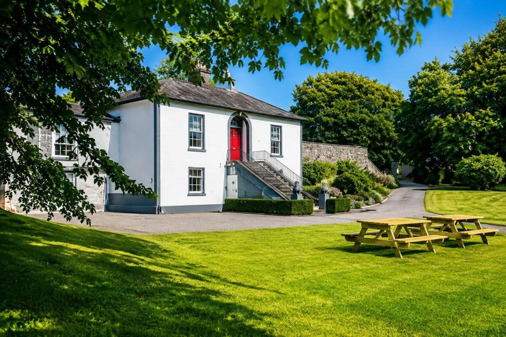 a house with a red door and picnic tables in the grass at Nore View House in Kilkenny