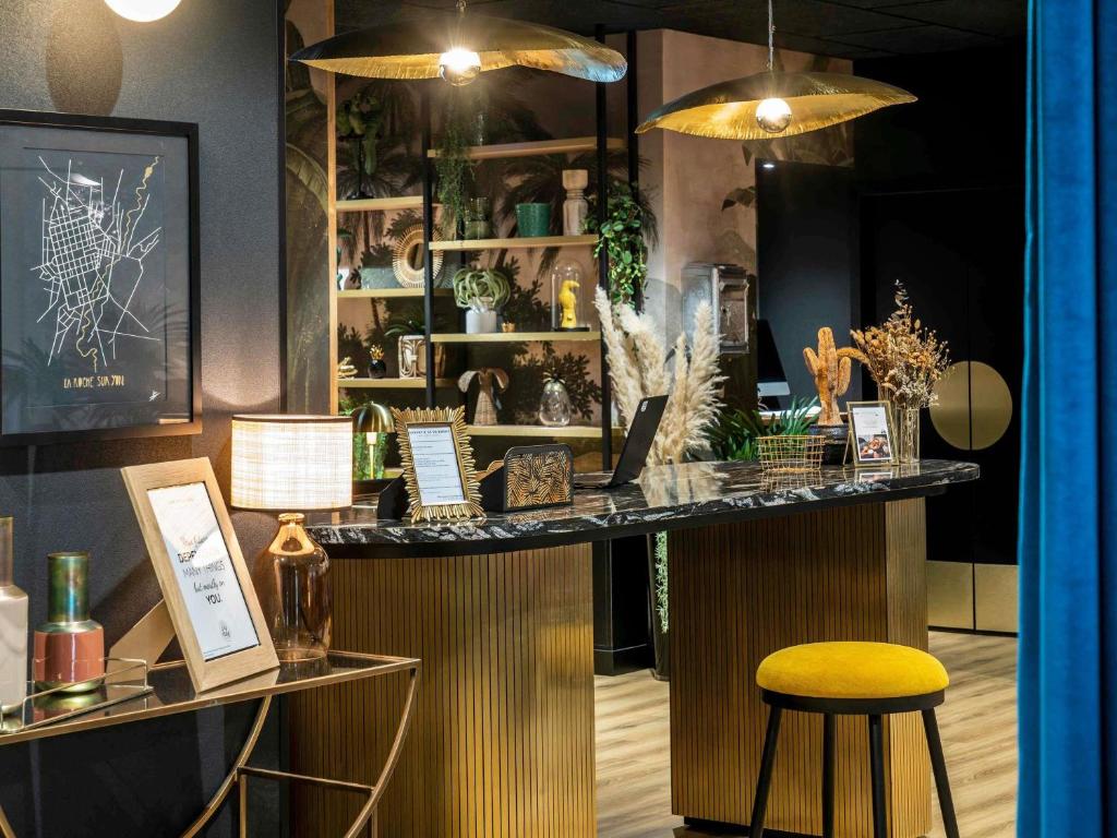 a bar in a room with a yellow stool at Mercure La Roche Sur Yon in La Roche-sur-Yon