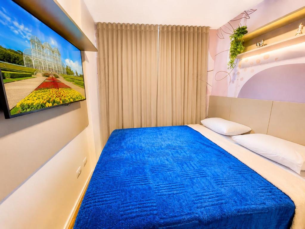 a bedroom with a bed with a tv on the wall at ＴＨＥ ＯＮＥ Studio! A Vɪʙᴇ Pᴇʀғᴇɪᴛᴀ ɴᴏ Lɪɴs C/Ar Cond in Curitiba