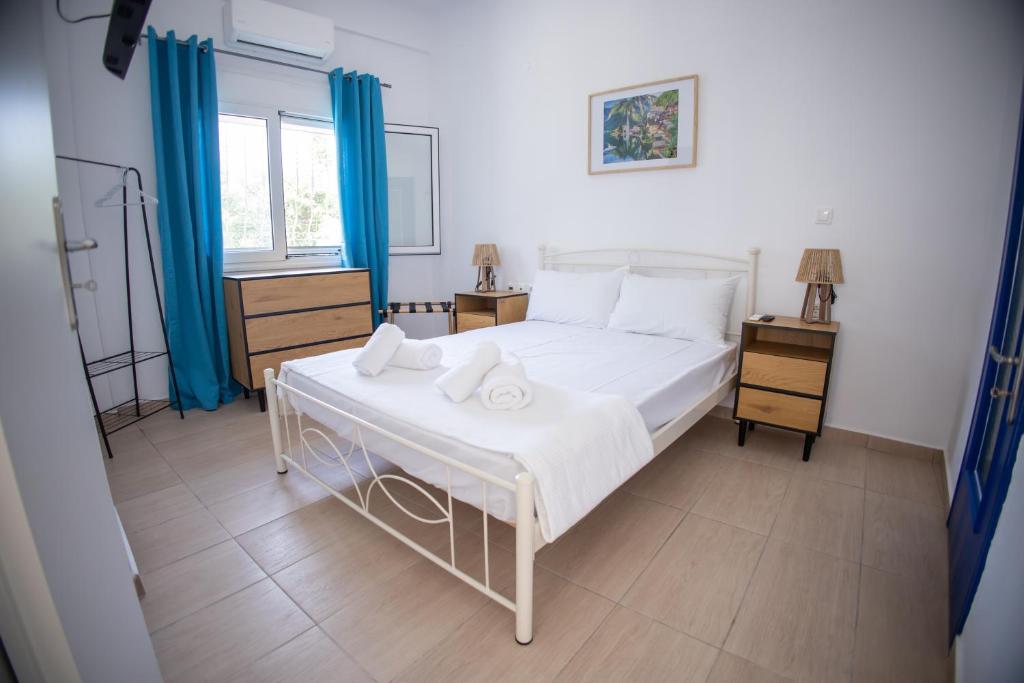 a bedroom with a white bed and blue curtains at Blue Water Escape in Agioi Theodoroi