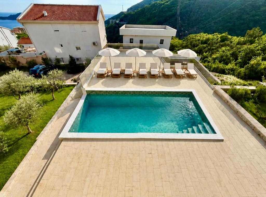 a swimming pool with chairs and a house at Vila Lavandel in Bečići