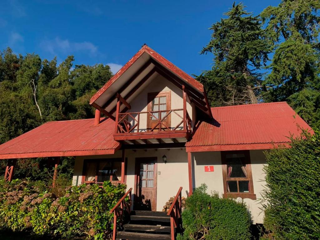 a house with a red roof and stairs leading to it at Cabañas El Nuevo Cimarrón in Puerto Varas