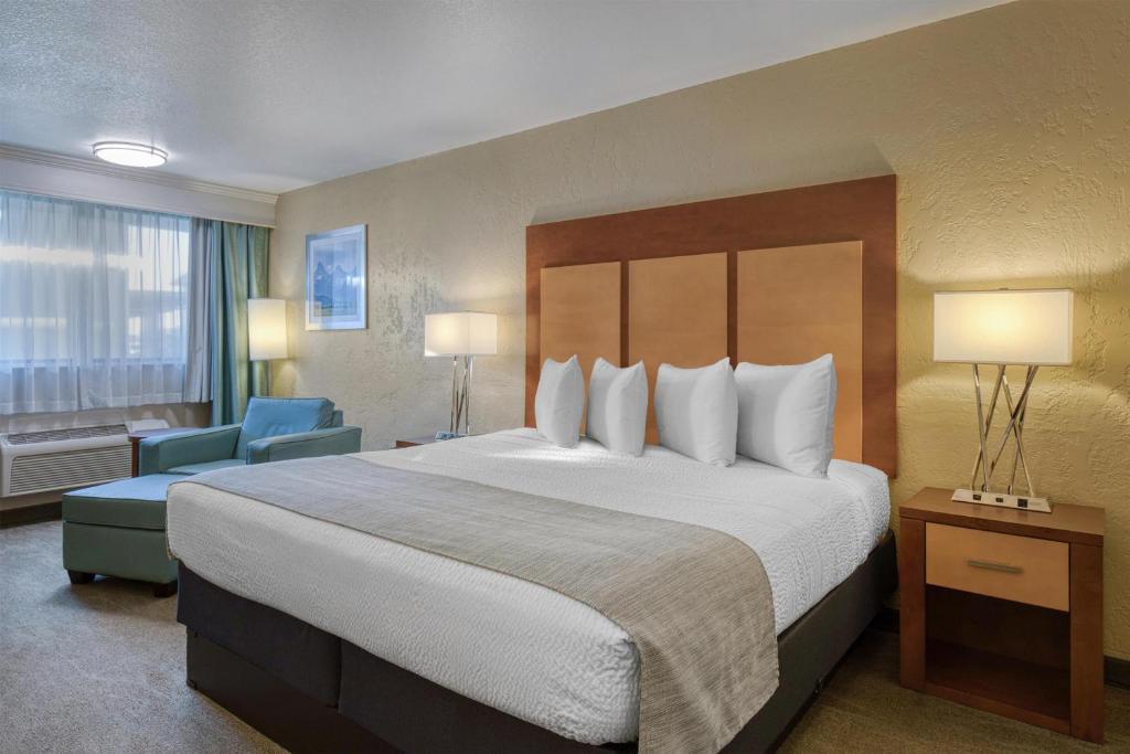 a hotel room with a large bed and a blue chair at Best Western Foothills Inn in Mountain Home