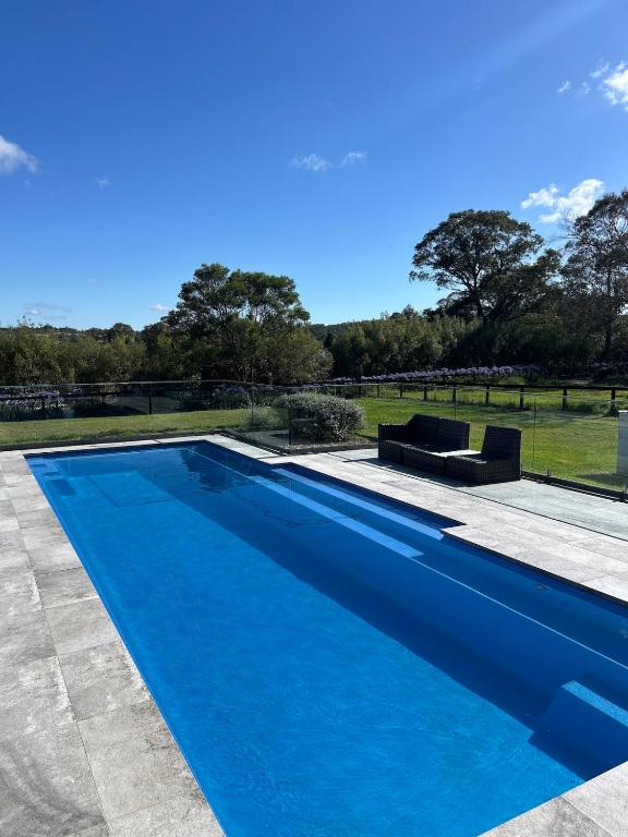a blue swimming pool in a yard with trees in the background at Kalamunda Estate with Pool, Fire Pit & BBQ Deck in Bundanoon