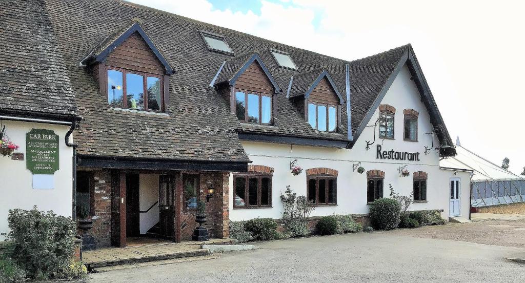 um grande edifício branco com um telhado preto em The Airman Hotel em Shefford