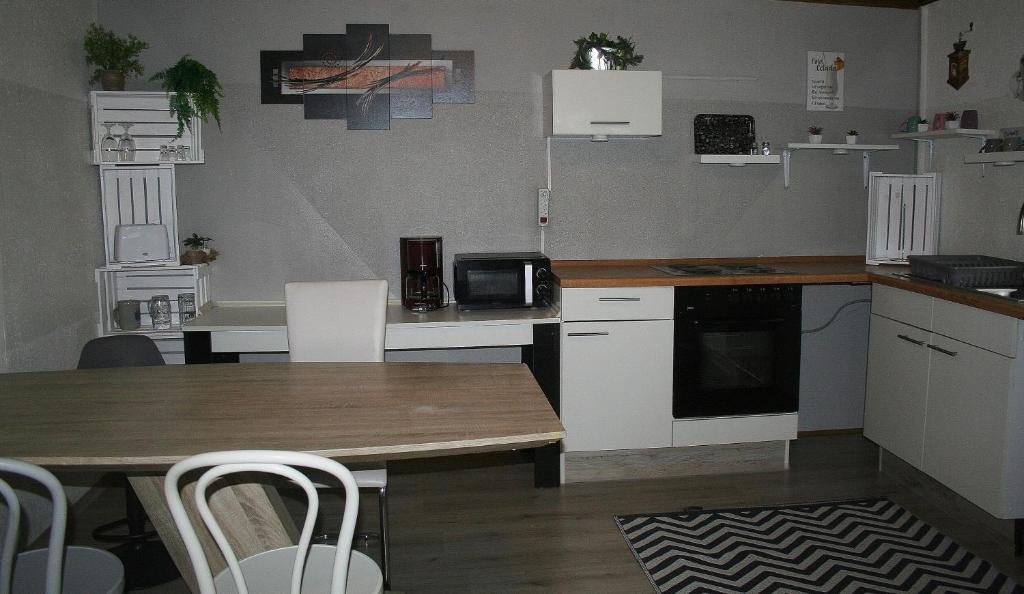 a kitchen with a wooden table and white cabinets at Ferienwohnung Hexenhäusla in Gößweinstein