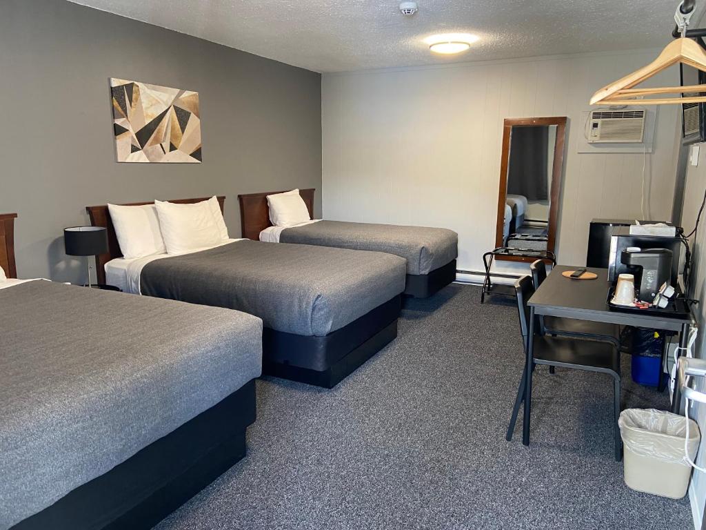a hotel room with two beds and a desk at Monashee Lodge in Revelstoke