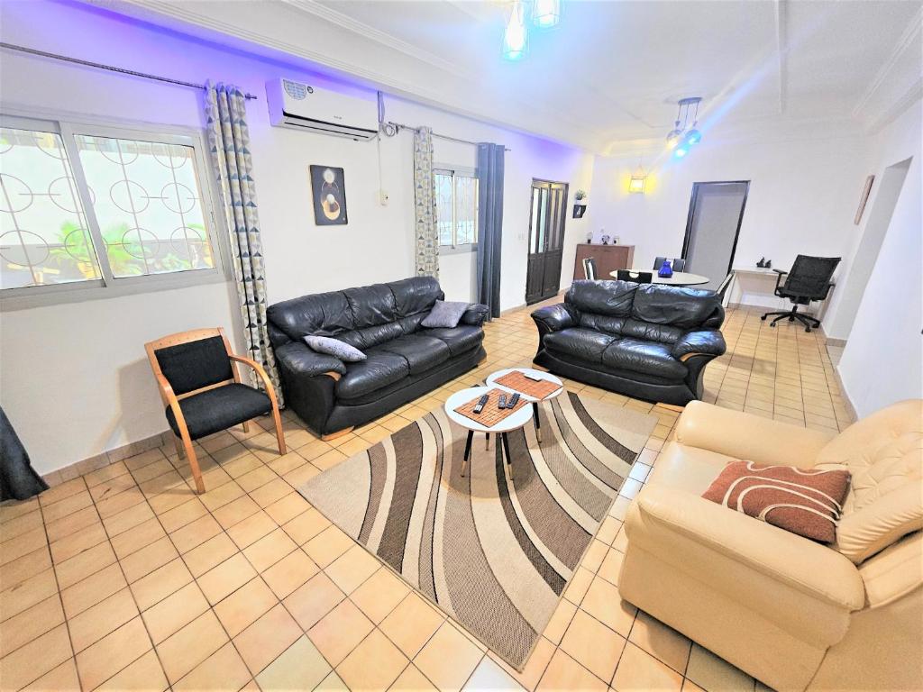 a living room with leather couches and a table at The Yafé Bastos 15 (Villa) in Yaoundé