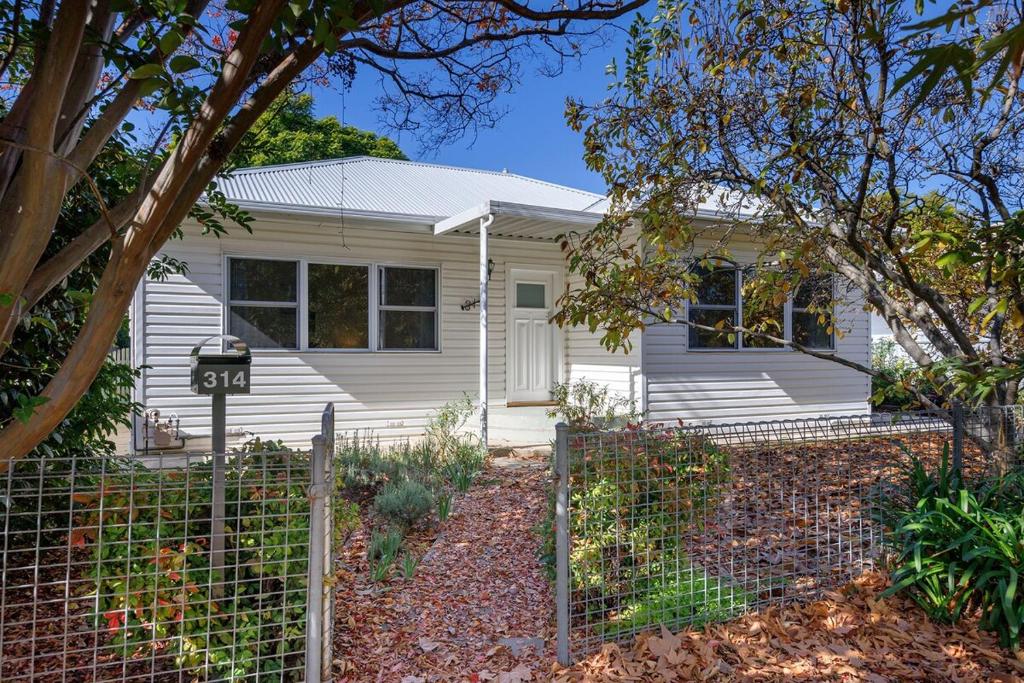 a white house with a fence in front of it at Delightful Digs on David in Albury