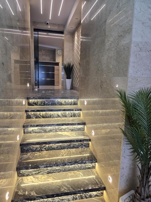 a lobby of a building with stairs and plants at Hotel Al Abraj in Oran