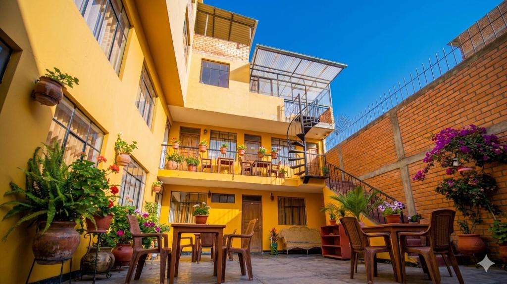 an outdoor patio with tables and chairs and a building at CAYESH Guest House in Huaraz
