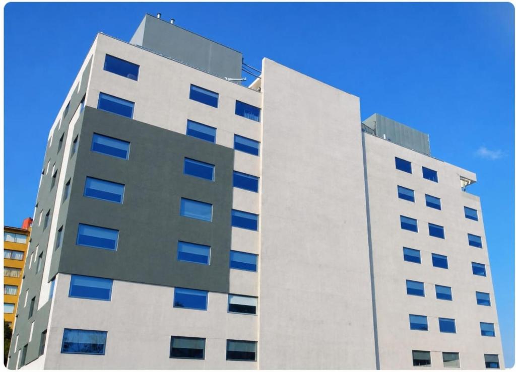 ein hohes weißes Gebäude mit blauen Fenstern in der Unterkunft Hotel Curico - Ex Radisson Curico in Curicó