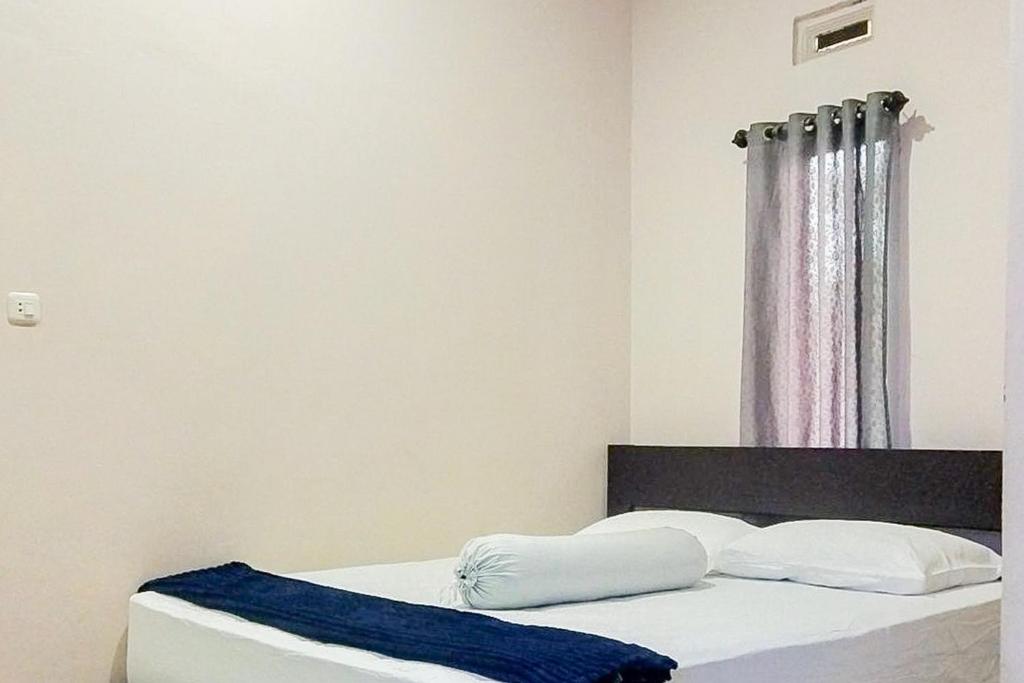 a bedroom with a bed with a blue blanket on it at RedDoorz at Morowali Sulawesi Tengah in Ulunipa
