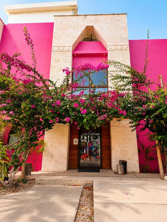 a pink building with flowers in front of it at Hotel Céntrico Tulum in Tulum