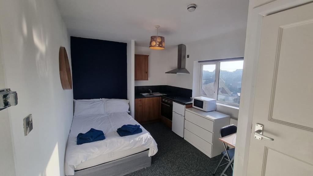 a small bedroom with a bed and a kitchen at Self-Contained Studio Private Bathroom Sleeps 2 in Nottingham