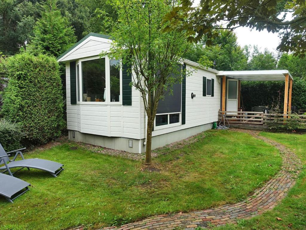 a small white cabin with a tree in the yard at Vechtdal Chalet de Eik in Rheezerveen