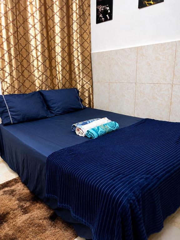 a bed with a blue comforter on top of it at Kitnet Dream House 2 in Bayeux