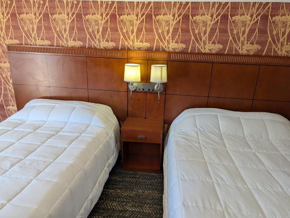 a bedroom with two beds and two lamps on the wall at Exceed Inn Indianapolis Airport South in Indianapolis