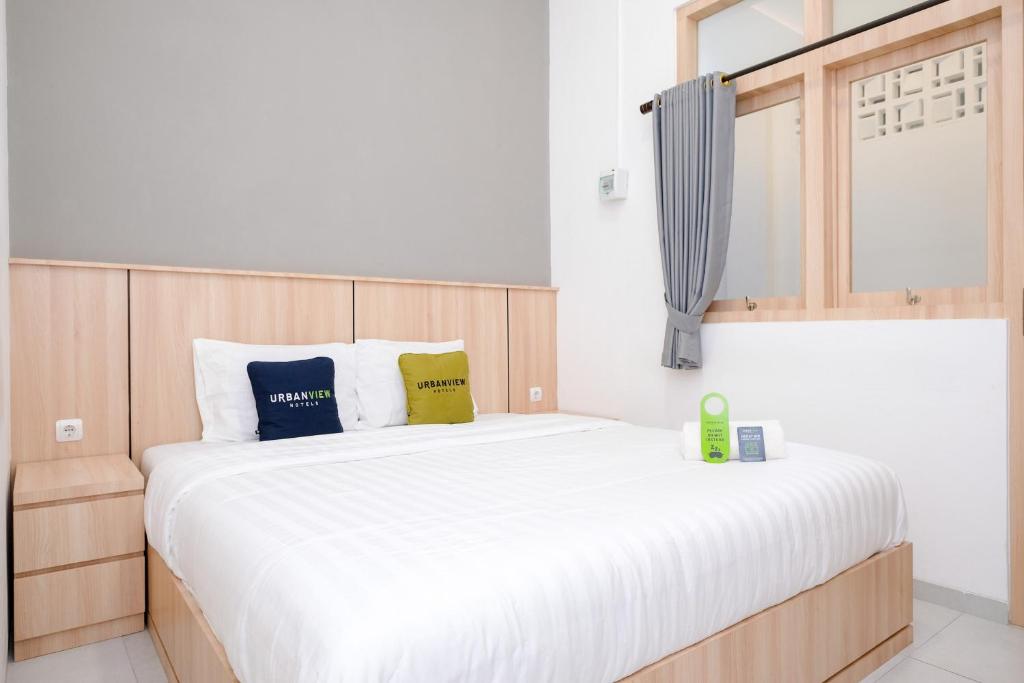 a bedroom with a large white bed with two pillows at Urbanview Hotel Subali Purwokerto in Purwokerto