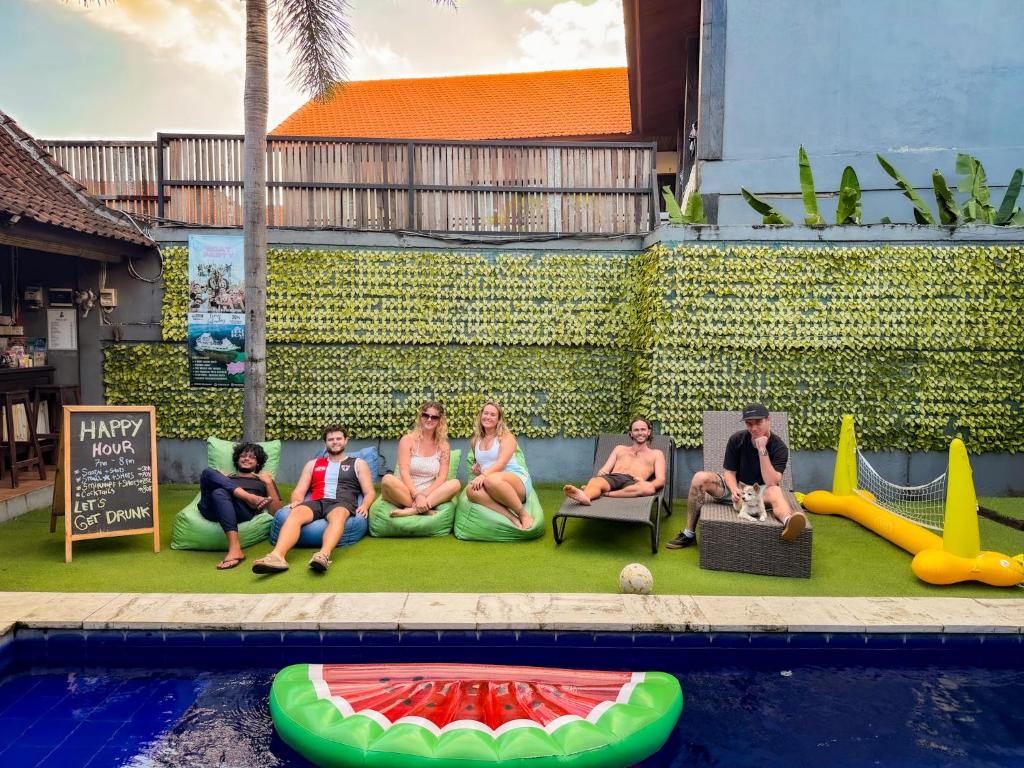 a group of people sitting on a couch next to a pool at The Tipsy Gypsy Hostel in Canggu