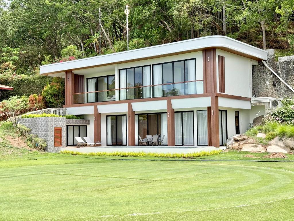 a house on a hill with a green yard at Royal Legacy Golf Private Villa in Rawai Beach