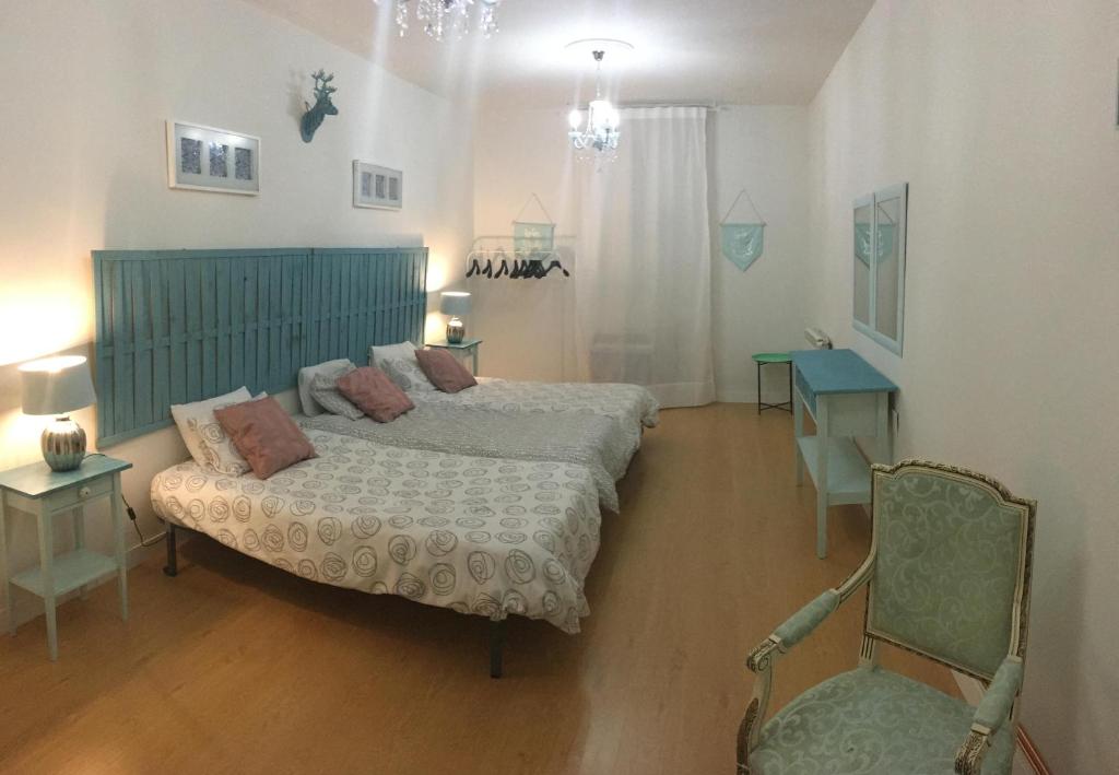 a bedroom with two beds and a chair at Apartamento Carreteria Luxe in Cuenca