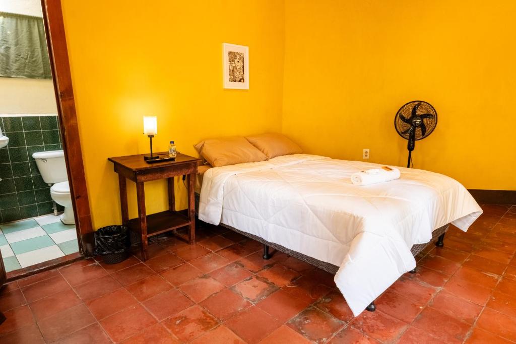 a bedroom with a bed and a bathroom with a toilet at Hotel Itzel in Cobán