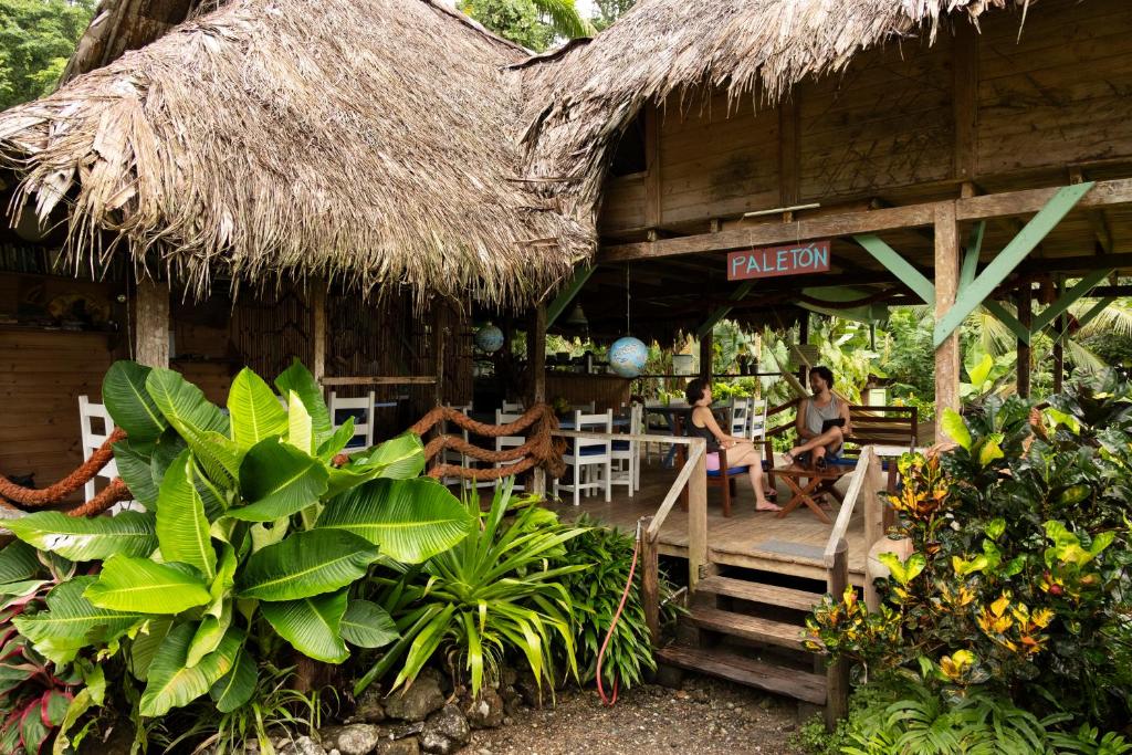 two people sitting on the porch of a hut at Hotel Pijibá Lodge in Nuquí