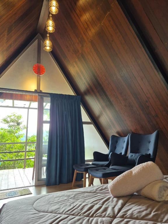 a bedroom with a bed and a chair and a window at Orchid Chalet in Ringlet