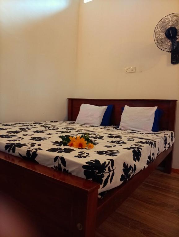 a bed with a black and white comforter with flowers on it at SEE CHAIN Resort in Digana