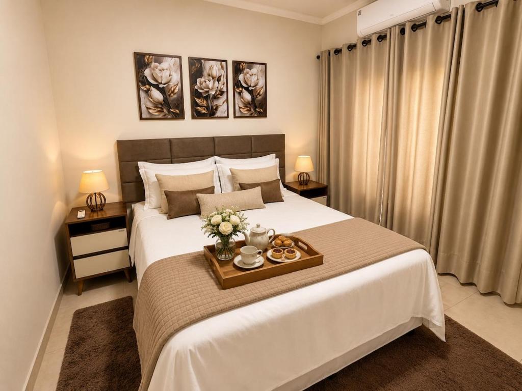 a bedroom with a bed with a tray with flowers on it at Flat 2 quartos em residencial | Ar e garagem in Ourinhos