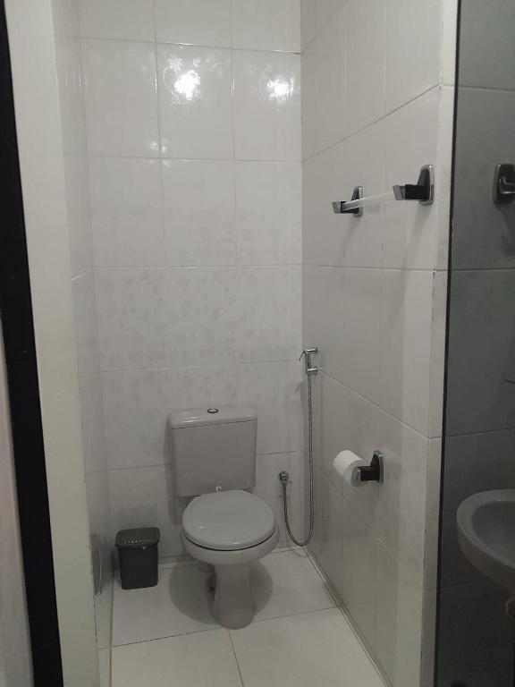 a white bathroom with a toilet and a sink at Casa temporada in Lençóis